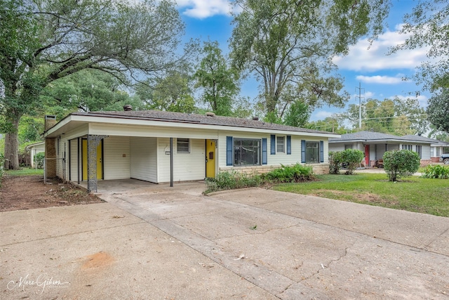 ranch-style house with concrete driveway, a carport, and a front yard