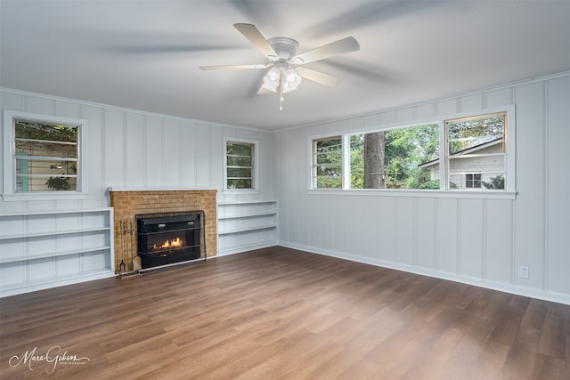 unfurnished living room with ceiling fan, a fireplace, built in features, and wood finished floors