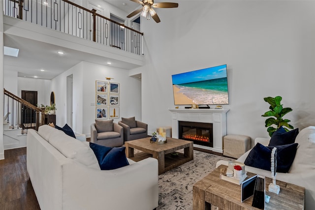 living room featuring a towering ceiling, hardwood / wood-style flooring, and ceiling fan