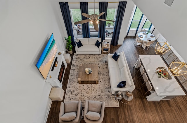 living room featuring dark hardwood / wood-style flooring, ceiling fan with notable chandelier, and plenty of natural light