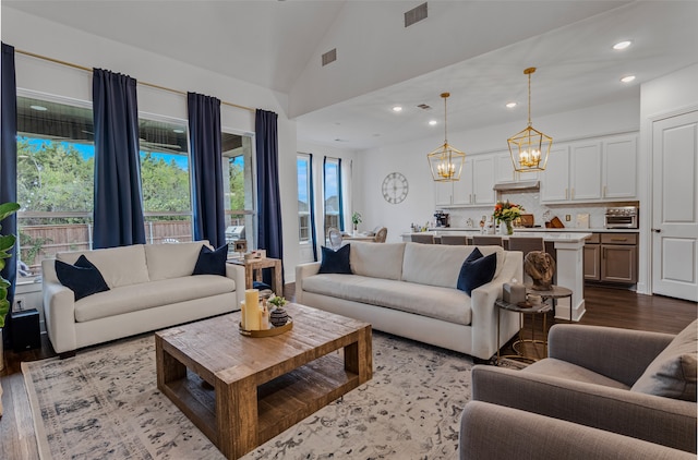 living room with light hardwood / wood-style floors, a chandelier, and high vaulted ceiling