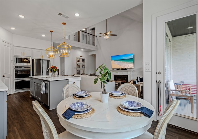 dining space featuring sink, dark wood-type flooring, and ceiling fan with notable chandelier