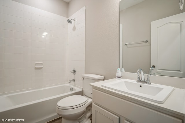 full bathroom featuring tiled shower / bath, vanity, and toilet