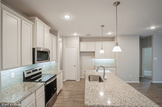 kitchen featuring hardwood / wood-style flooring, stainless steel appliances, sink, decorative light fixtures, and white cabinetry