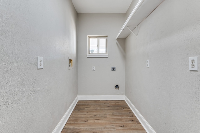 clothes washing area featuring electric dryer hookup, hookup for a washing machine, and light hardwood / wood-style flooring