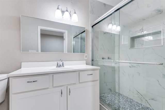 bathroom featuring a shower with door, vanity, and toilet