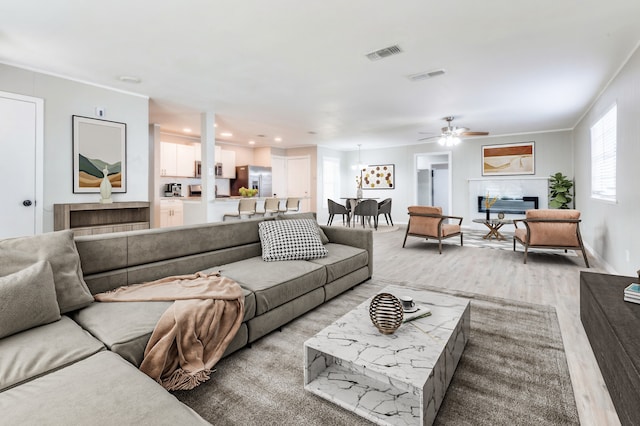 living room with light hardwood / wood-style floors, ceiling fan, and crown molding