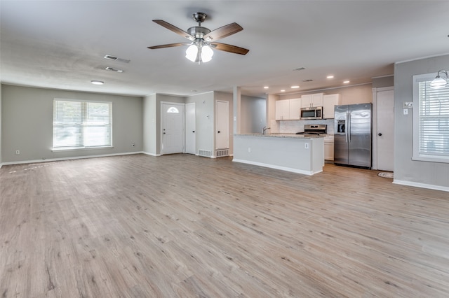 kitchen featuring light hardwood / wood-style flooring, ceiling fan, appliances with stainless steel finishes, light stone counters, and white cabinetry