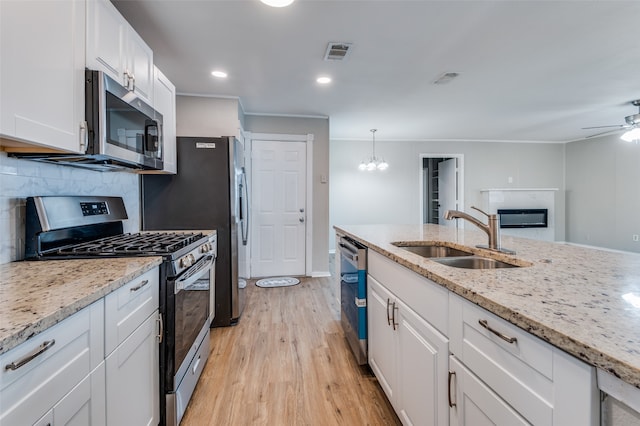 kitchen with light wood-type flooring, backsplash, stainless steel appliances, sink, and white cabinets