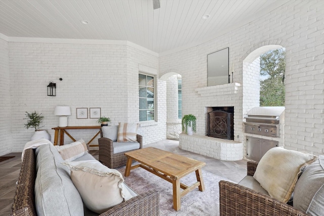 living room with an outdoor brick fireplace, wooden ceiling, and brick wall