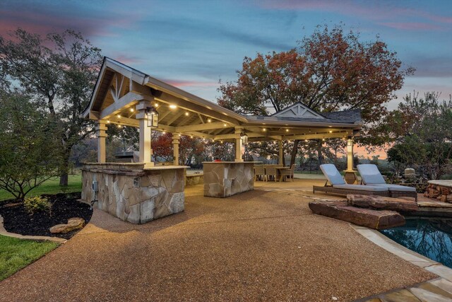 patio terrace at dusk with an outdoor living space with a fireplace and french doors