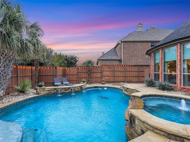 pool at dusk with an in ground hot tub and pool water feature