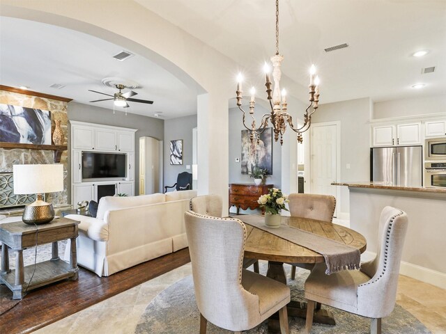 living room with ceiling fan, dark wood-type flooring, and a stone fireplace