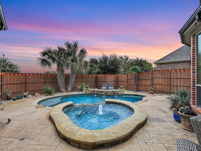 pool at dusk featuring pool water feature, a patio area, and an in ground hot tub