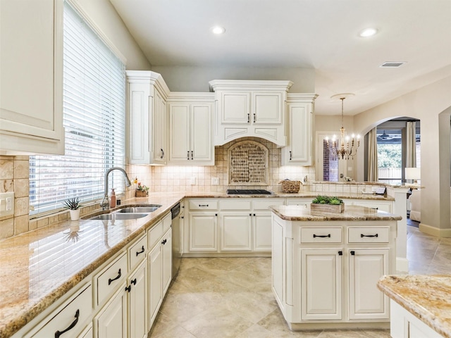 kitchen with decorative light fixtures, sink, light stone counters, and stainless steel appliances