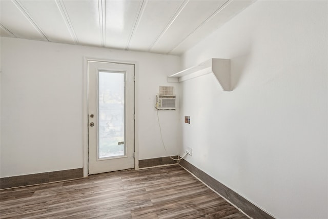 laundry room with hookup for a washing machine, hardwood / wood-style floors, and an AC wall unit