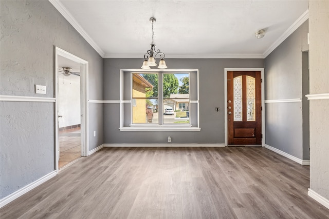 foyer entrance with ornamental molding, wood-type flooring, and ceiling fan with notable chandelier