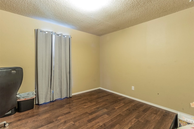 empty room featuring dark wood-type flooring and a textured ceiling