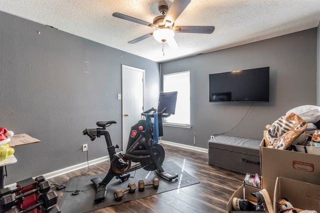 exercise area featuring ceiling fan, dark hardwood / wood-style floors, and a textured ceiling