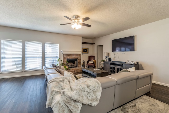 living room featuring ceiling fan, dark hardwood / wood-style flooring, a fireplace, and a textured ceiling