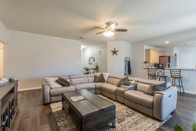 living room featuring a textured ceiling, dark hardwood / wood-style floors, and ceiling fan