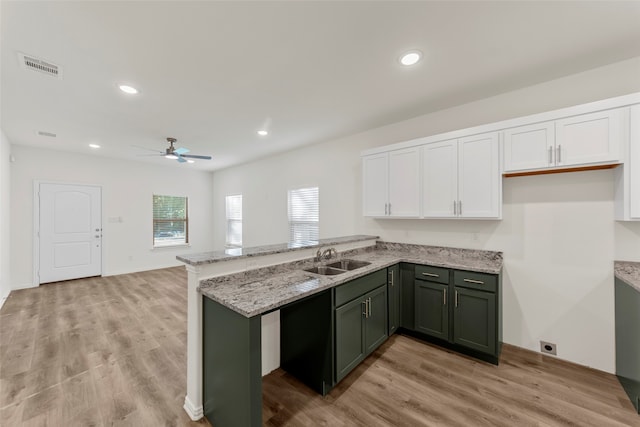 kitchen with white cabinets, ceiling fan, green cabinets, light wood-type flooring, and light stone counters