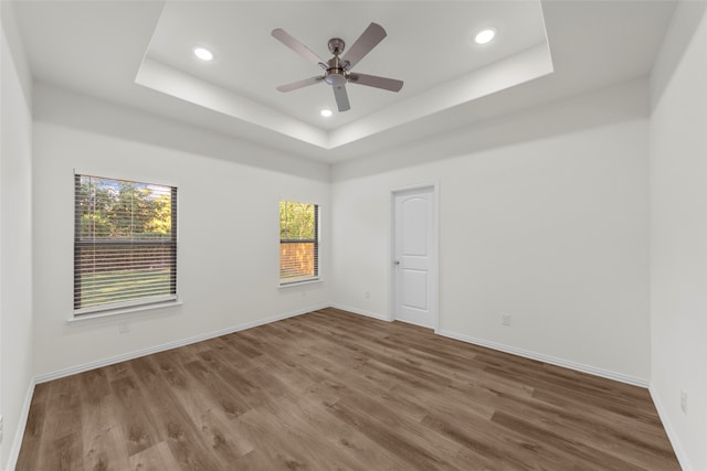 spare room featuring a raised ceiling, hardwood / wood-style flooring, and ceiling fan