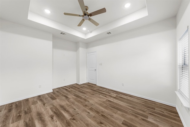 spare room with a raised ceiling and dark hardwood / wood-style floors