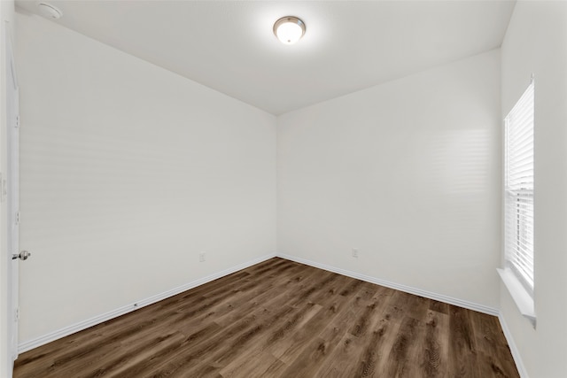 spare room featuring dark wood-type flooring and plenty of natural light