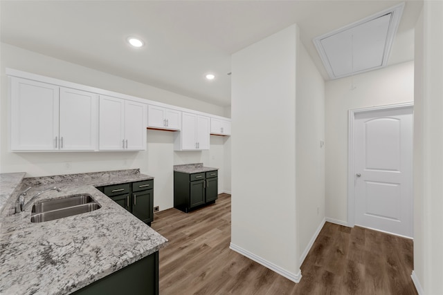 kitchen featuring hardwood / wood-style floors, sink, white cabinets, and light stone countertops