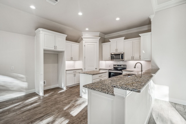 kitchen with kitchen peninsula, stainless steel appliances, white cabinetry, and sink