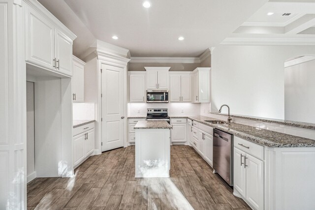 kitchen featuring kitchen peninsula, sink, appliances with stainless steel finishes, light hardwood / wood-style floors, and white cabinetry