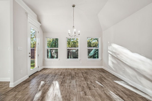 unfurnished dining area with a chandelier, plenty of natural light, hardwood / wood-style floors, and vaulted ceiling