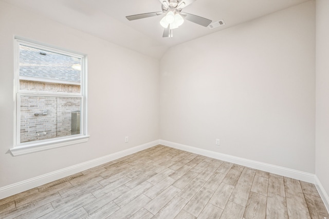 spare room with light wood-type flooring, vaulted ceiling, and ceiling fan