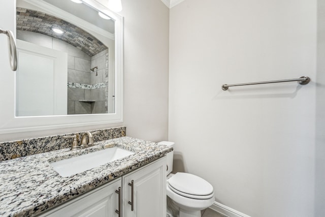 bathroom featuring tiled shower, vanity, toilet, and crown molding