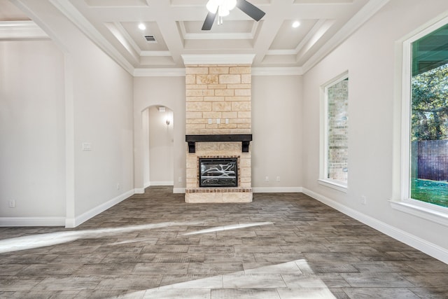 unfurnished living room featuring coffered ceiling, crown molding, ceiling fan, a fireplace, and beamed ceiling