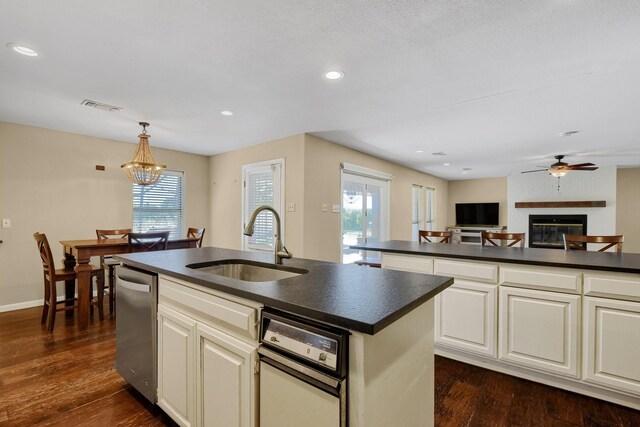 1062 Jp Cave Rd, Sherman, TX 75090 - kitchen featuring a sink, dark countertops, dishwasher, a large fireplace, and a kitchen island with sink