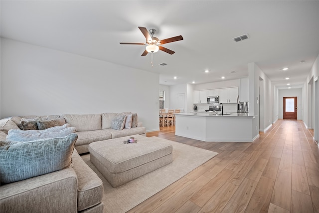 living room with sink, ceiling fan, and light hardwood / wood-style flooring