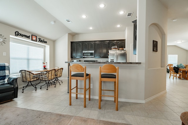 602 Tumbleweed Dr, Forney, TX 75126 - kitchen featuring stainless steel appliances, a breakfast bar area, lofted ceiling, healthy amount of natural light, and light tile patterned floors