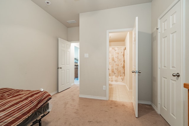 unfurnished bedroom featuring light carpet and ensuite bath