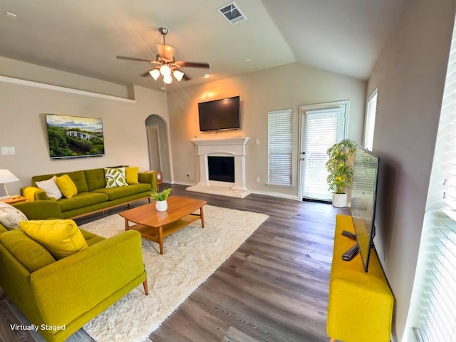 602 Tumbleweed Dr, Forney, TX 75126 - living area featuring ceiling fan, dark wood-style floors, a fireplace with raised hearth, vaulted ceiling, and arched walkways