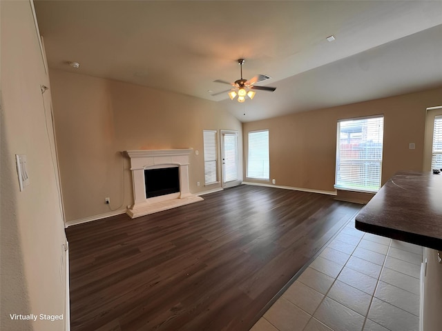 602 Tumbleweed Dr, Forney, TX 75126 - unfurnished living room with wood finished floors, plenty of natural light, ceiling fan, a fireplace with raised hearth, and vaulted ceiling