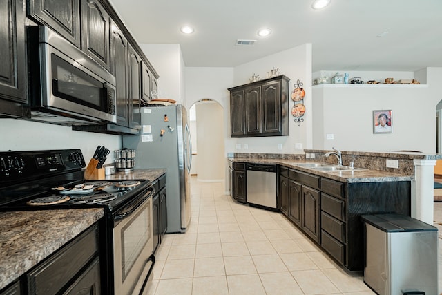 kitchen with sink, appliances with stainless steel finishes, dark stone countertops, and light tile patterned floors