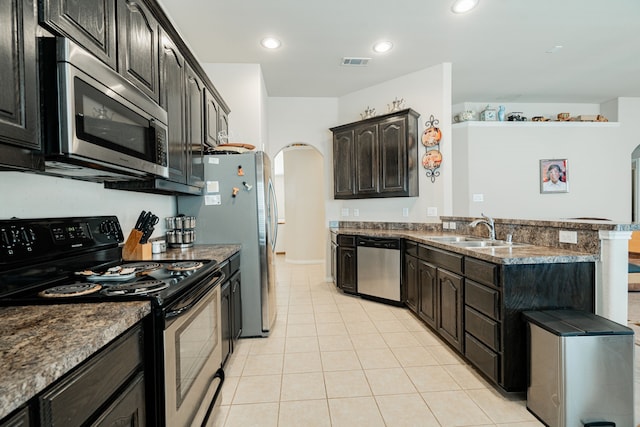 602 Tumbleweed Dr, Forney, TX 75126 - kitchen with stainless steel appliances, arched walkways, light tile patterned floors, a peninsula, and recessed lighting