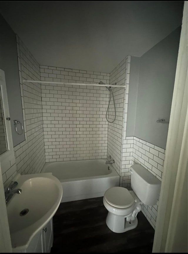 full bathroom featuring toilet, wood-type flooring, tiled shower / bath combo, tile walls, and vanity