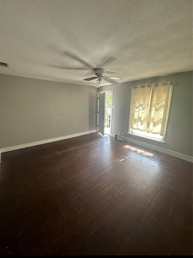 unfurnished room with a textured ceiling, dark wood-type flooring, and ceiling fan