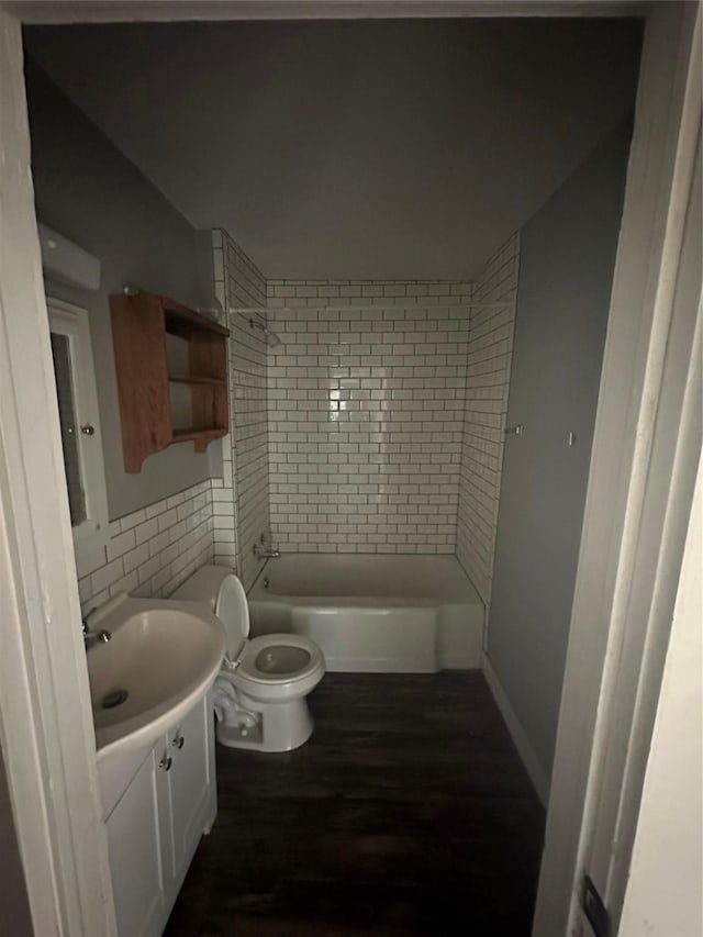 full bathroom featuring tiled shower / bath, hardwood / wood-style floors, tile walls, toilet, and vanity