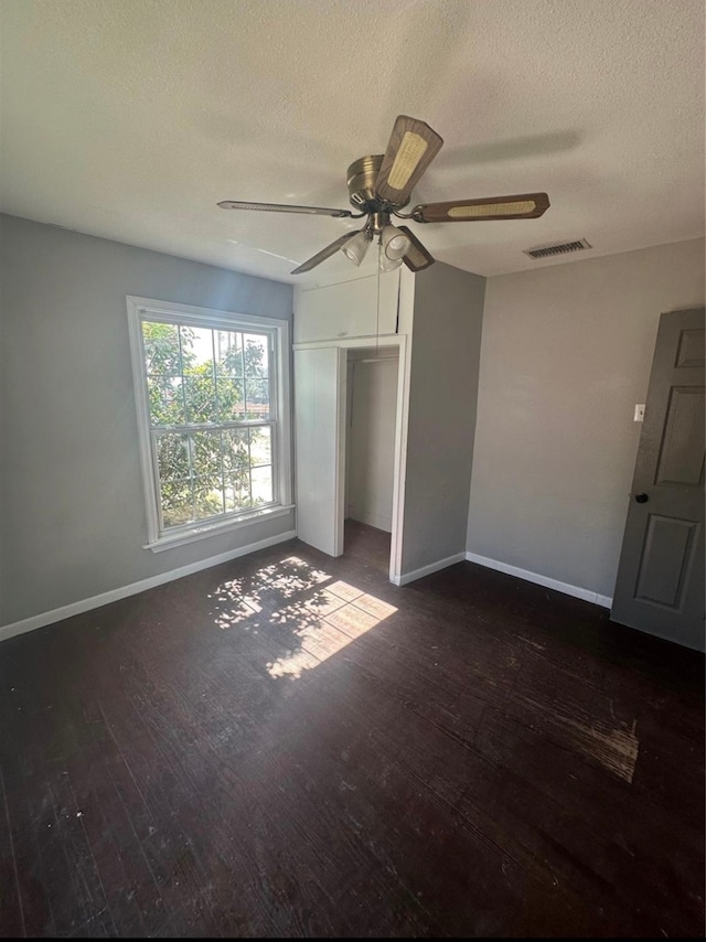 unfurnished bedroom featuring a textured ceiling, dark hardwood / wood-style floors, a closet, and ceiling fan