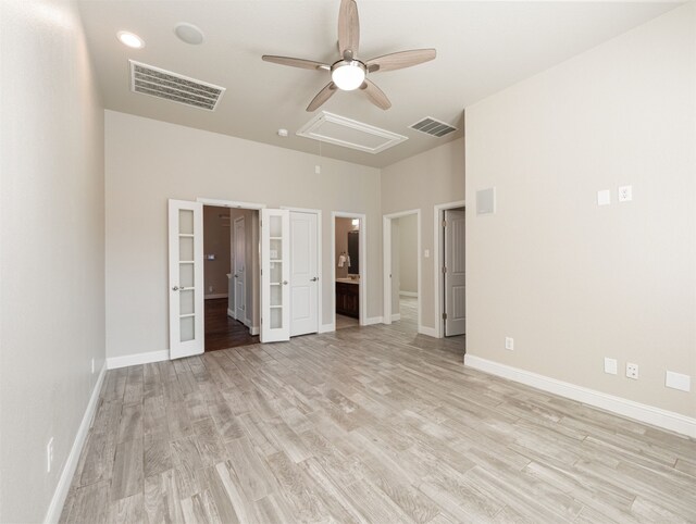 unfurnished bedroom featuring a walk in closet, light wood-type flooring, ensuite bathroom, and ceiling fan