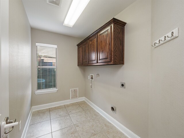 laundry area with electric dryer hookup, hookup for a washing machine, light tile patterned floors, and cabinets